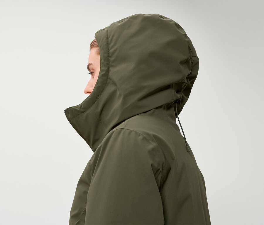 Profil kobiety w oliwkowej kurtce z kapturem.