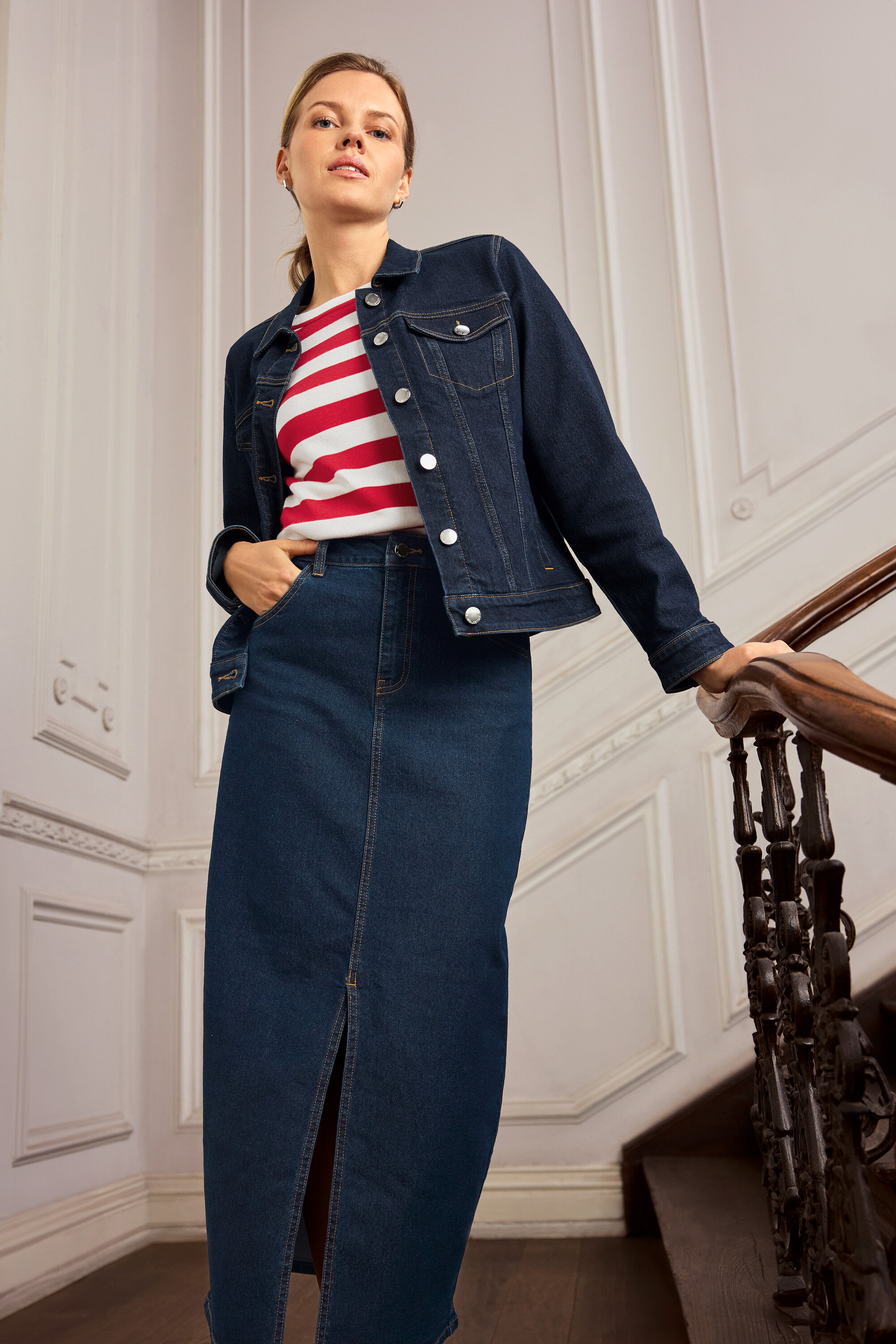 Kobieta w dżinsowej kurtce i spódnicy pozuje na schodach. Nosi kolczyki 925 Silver Creolen Hexagon.