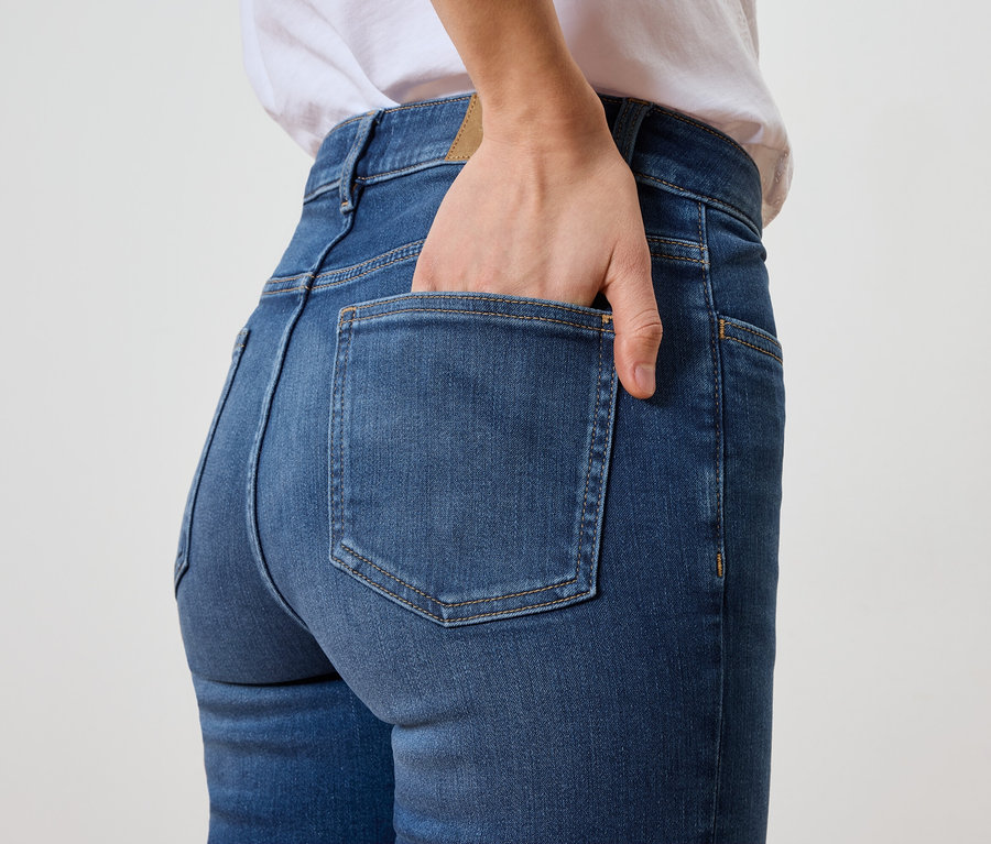 Kobieta trzyma rękę w tylnej kieszeni niebieskich dżinsów.