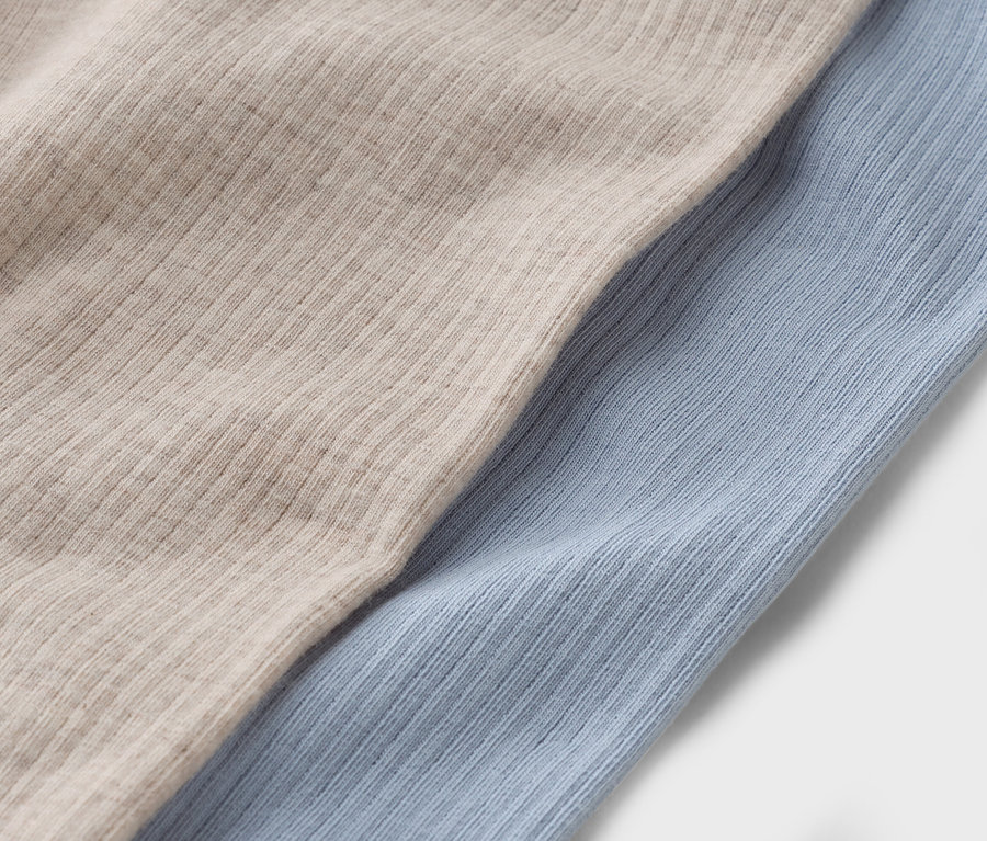 Zbliżenie na dwa kawałki materiału: beżowy i jasnoniebieski.