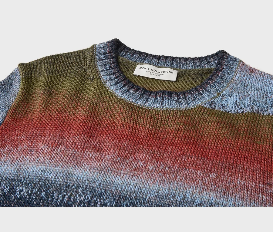 Dzianinowy sweter męski ombre, przechodzący od oliwkowej zieleni do czerwieni, a następnie jasnego i ciemnego błękitu. Metka "MEN'S COLLECTION by TCHIBO" na kołnierzu.