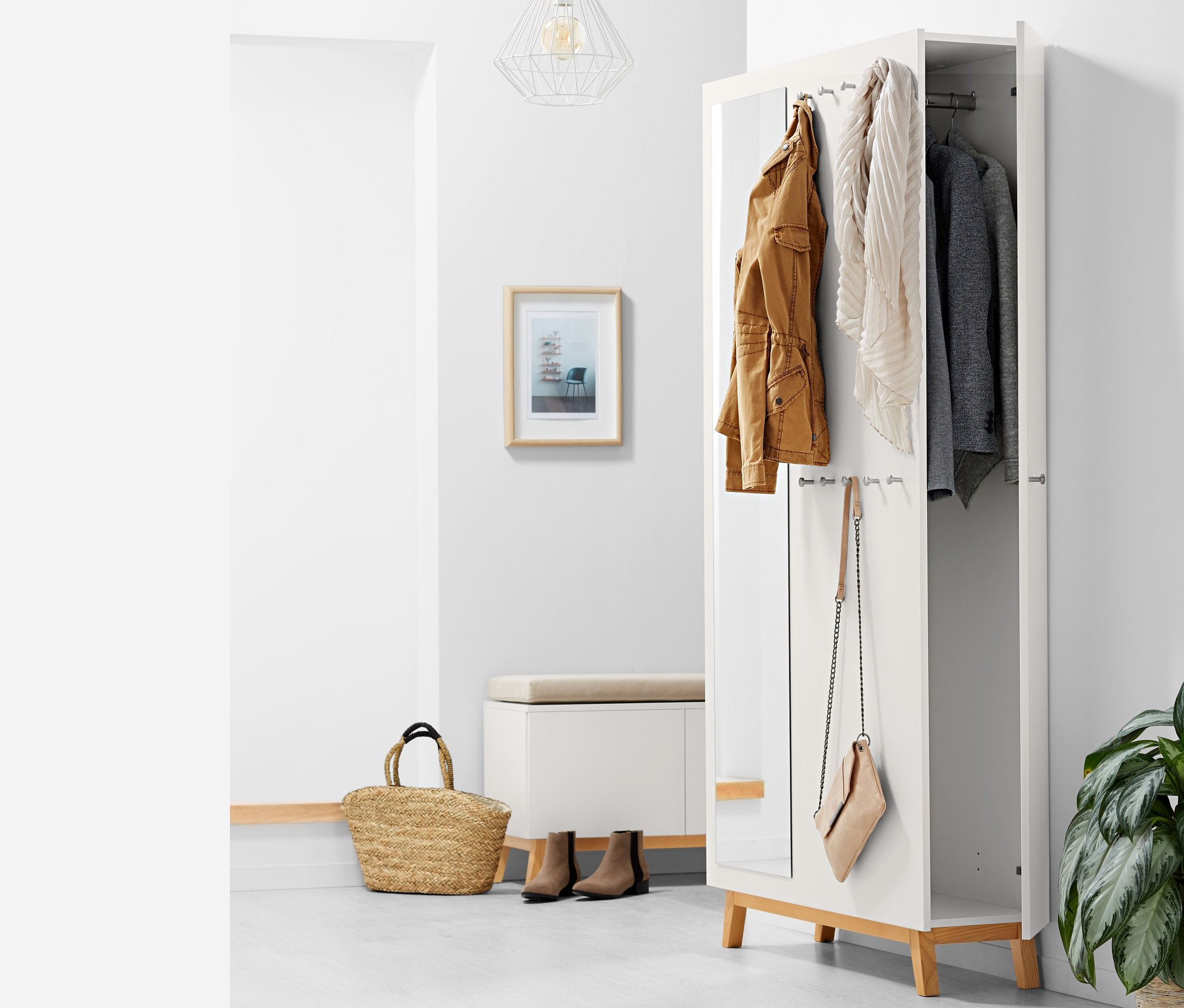 Otwarta wielofunkcyjna szafa do przedpokoju z brązową kurtką, szalikiem i szarą marynarką wiszącą w środku, z boku wisi torebka.