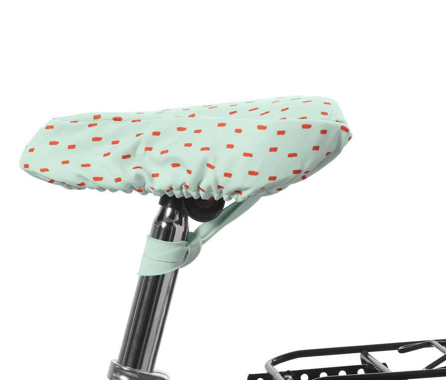 Pokrowiec na siodełko rowerowe dla dzieci, w kolorze miętowym, pokryty czerwonymi prostokątami.