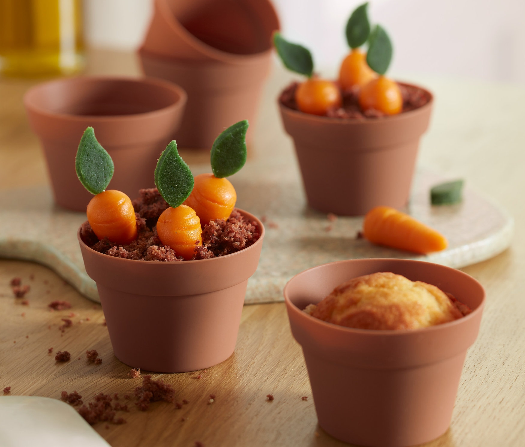 Muffiny w foremkach do muffinów, 6 sztuk, niektóre ozdobione marchewkami i zielonymi listkami.