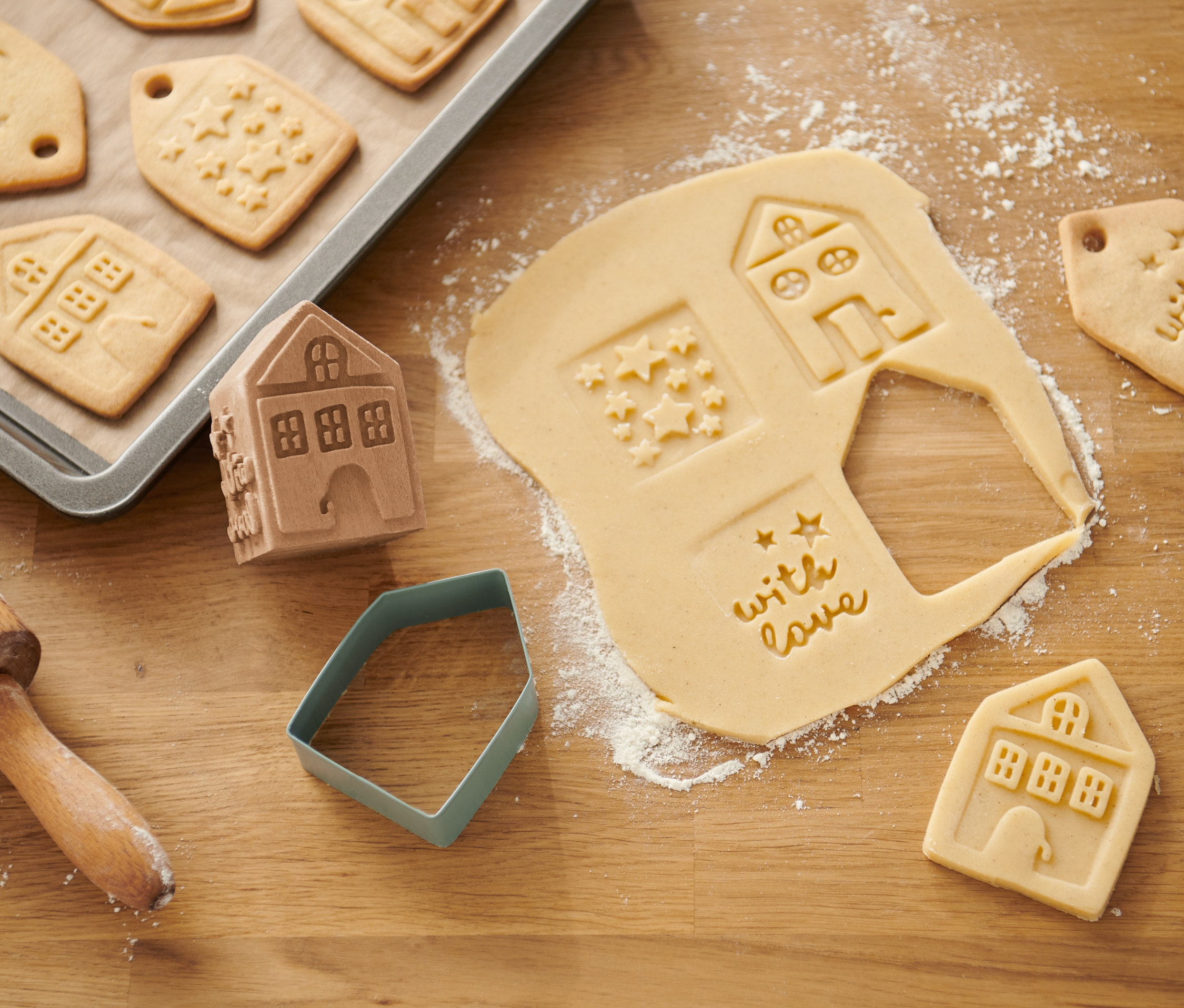 Zestaw stempelków do ciastek z motywami domu, gwiazdy i napisem "with love" na drewnianym stole.