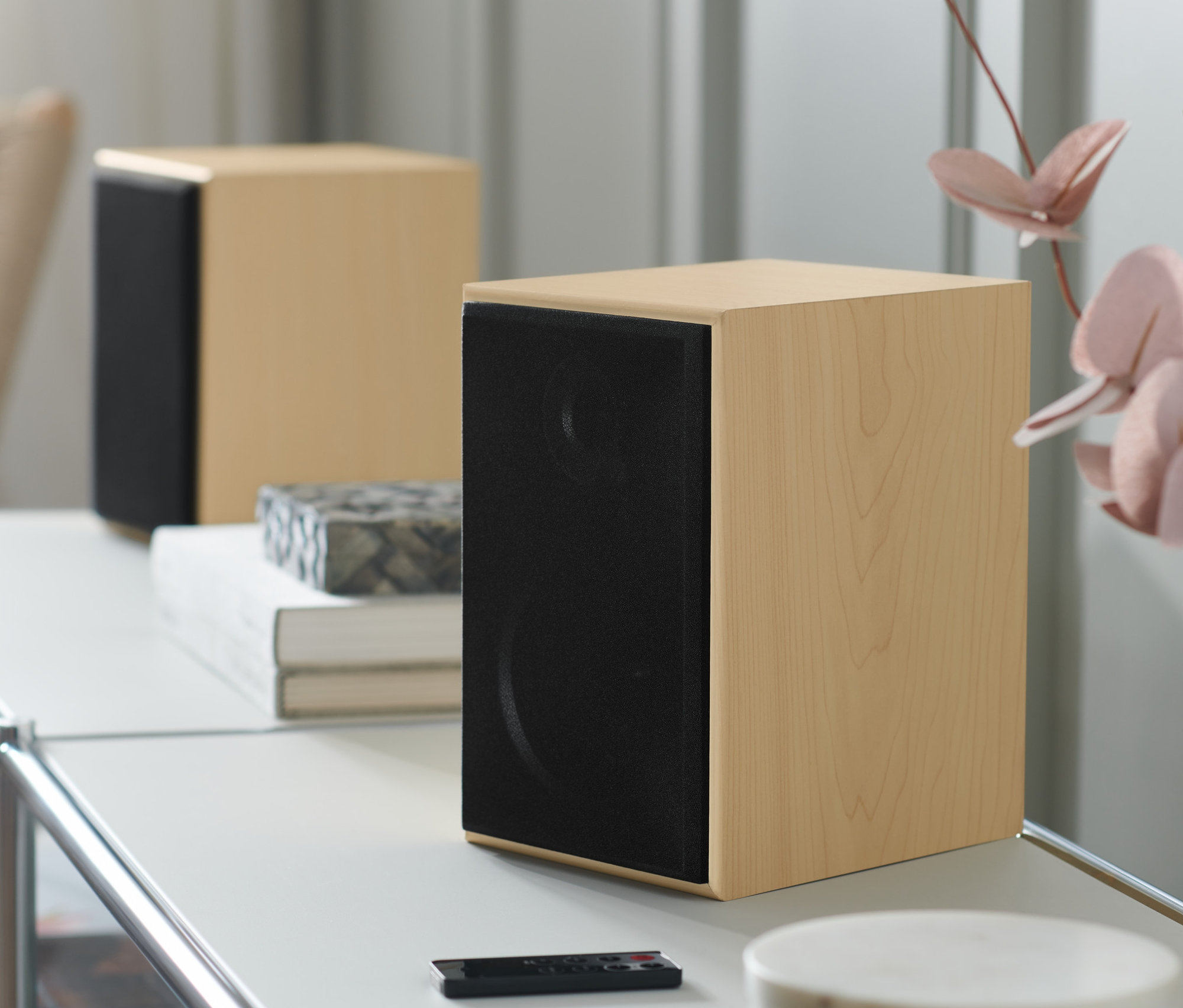 Dwa głośniki stojące stereo z Bluetooth® na białym stole z pilotem.