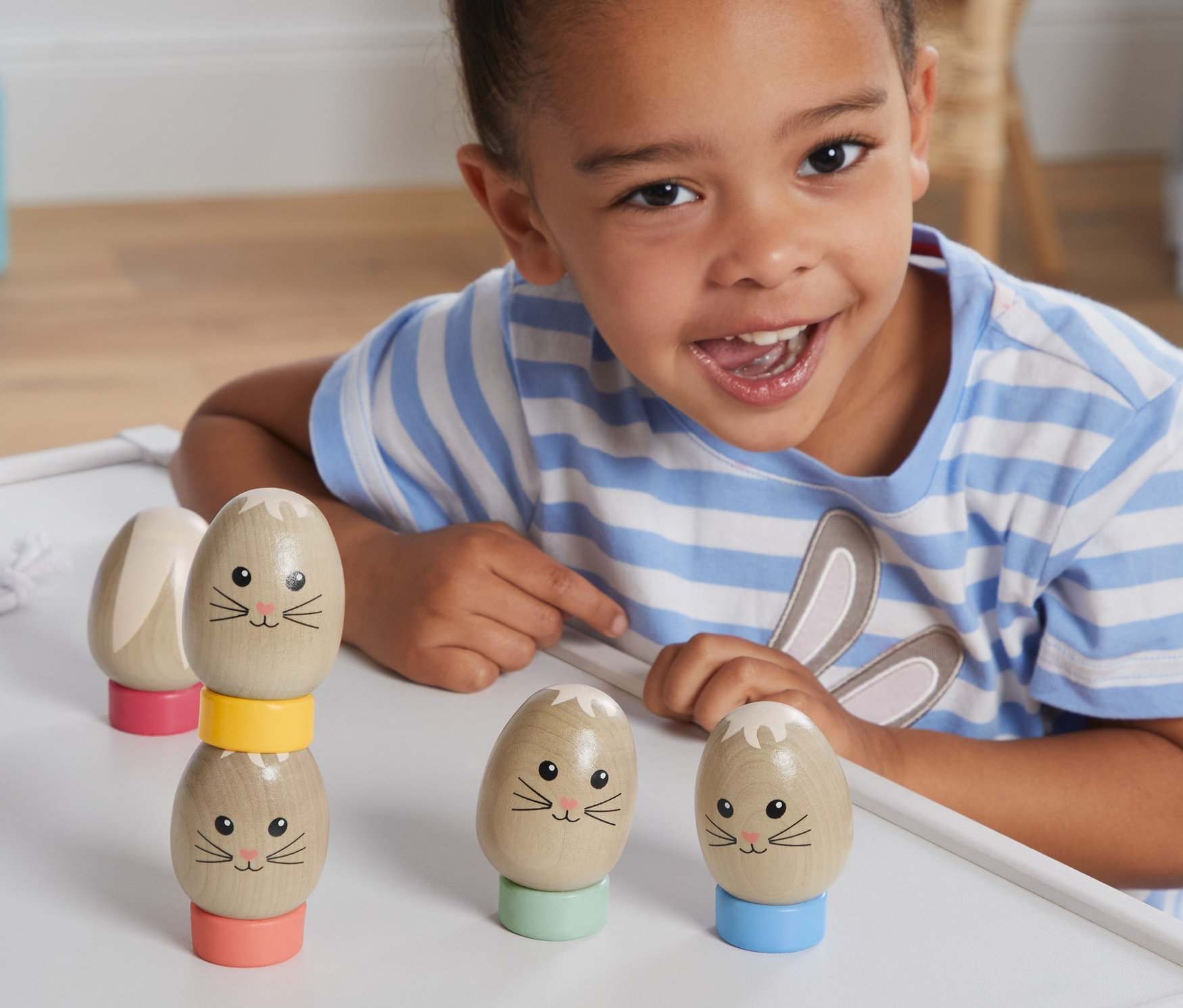 Uśmiechnięta dziewczynka bawi się zabawką – piramidą z jajek.