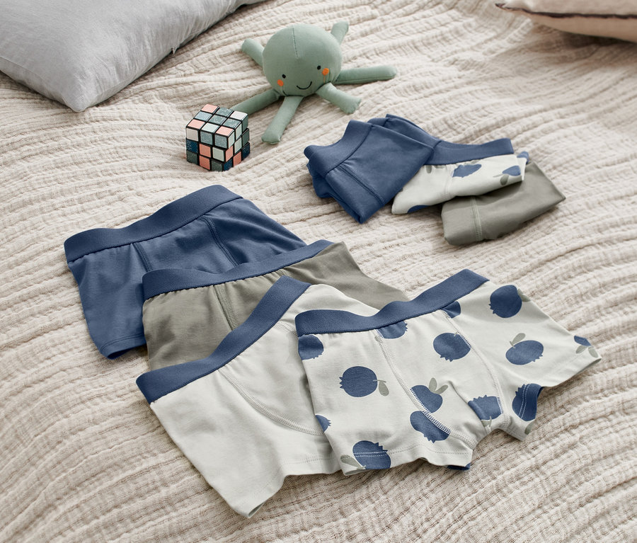 Na łóżku leżą bokserki, 7 sztuk, pluszowa ośmiornica i kostka.