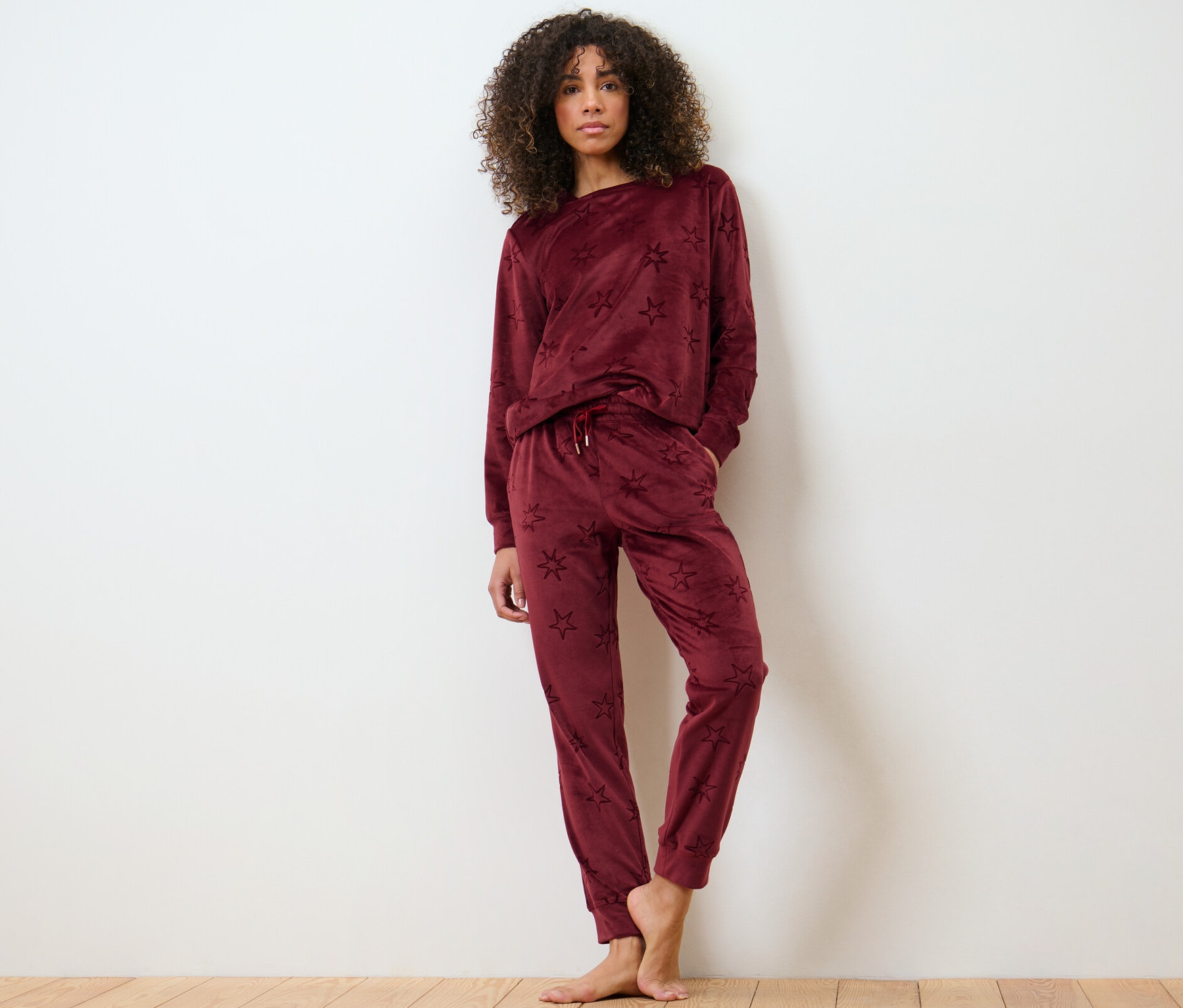 Kobieta pozuje na drewnianej podłodze w dresie domowym z weluru.