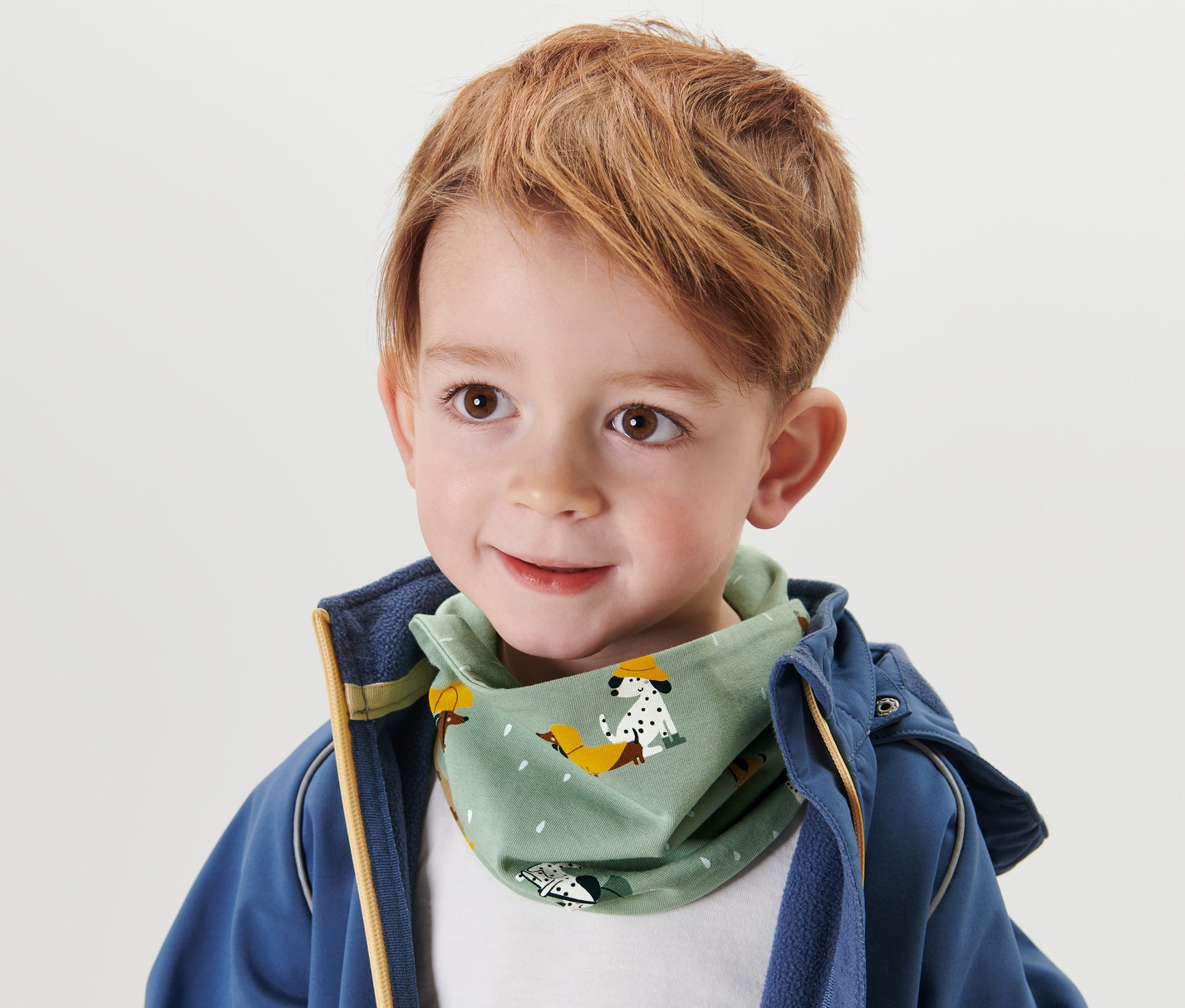 Chłopiec z brązowymi włosami w szaliku dziecięcym z rzepem.