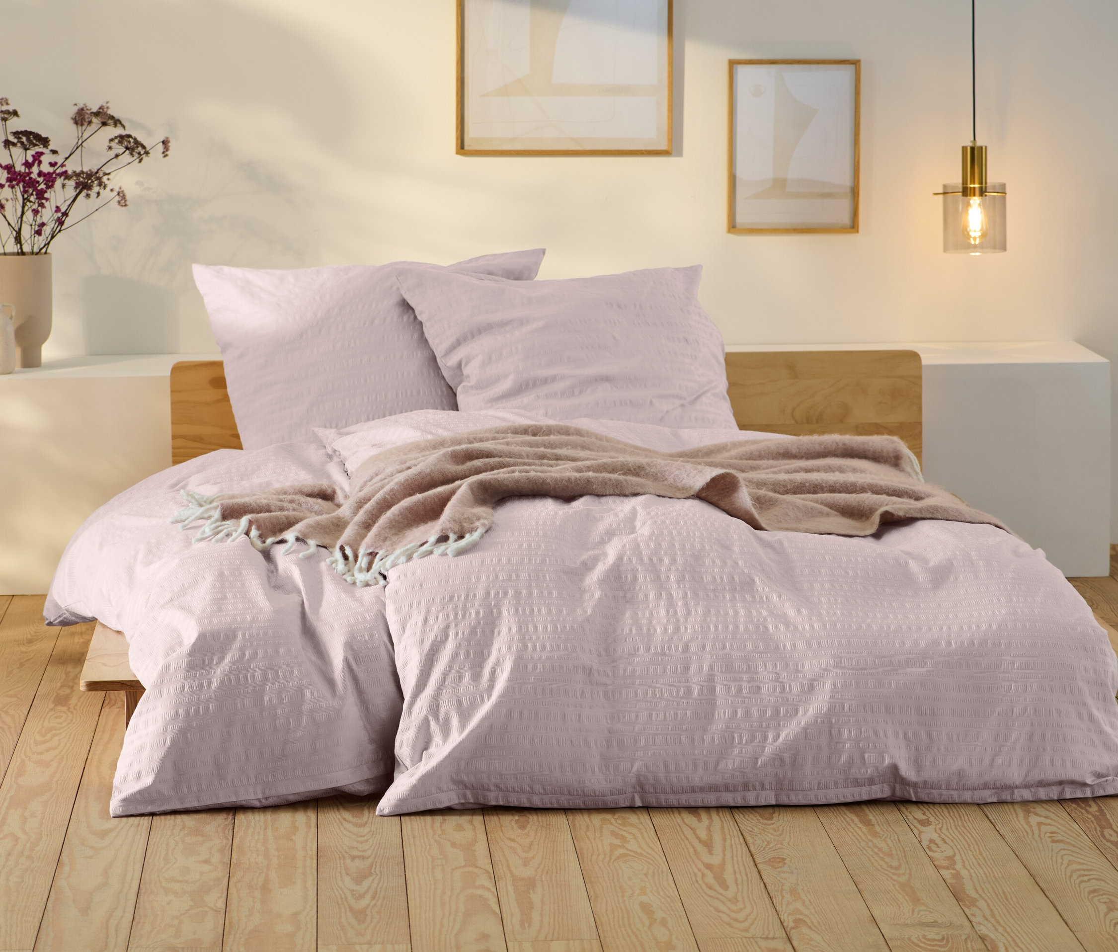 Bladoróżowa pościel z kory w standardowym i niestandardowym rozmiarze na łóżku z drewnianą ramą.