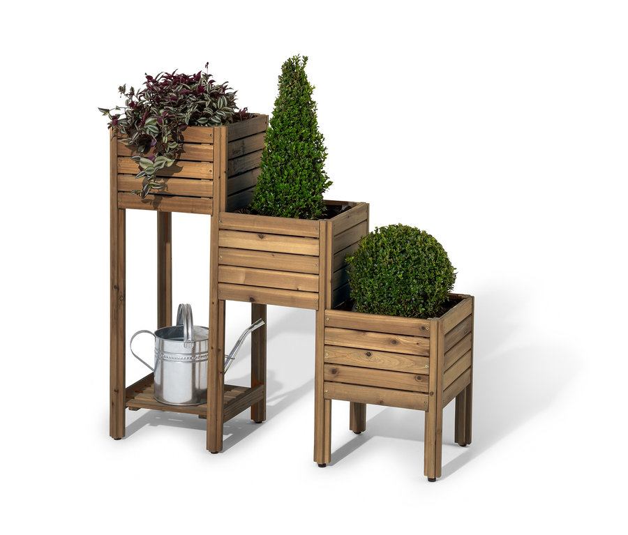 Drewniany stojak schodkowy na rośliny z półką „Tinus” z trzema roślinami i srebrną konewką do podlewania pod spodem.