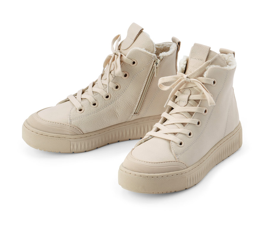 Dwa beżowe ocieplane buty typu sneakers ze skóry na białym tle.