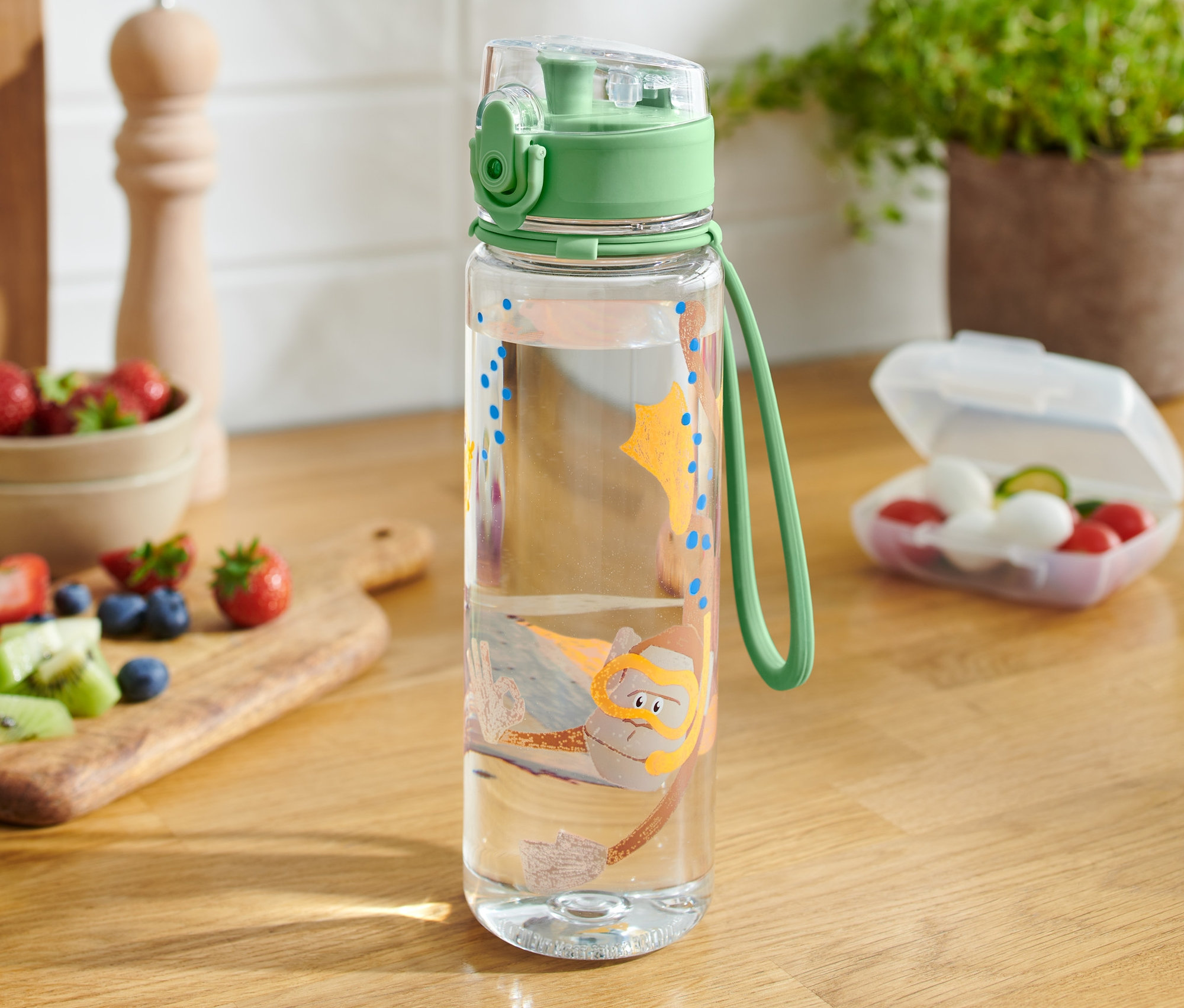 Przezroczysty bidon z motywem nurka stoi na drewnianym stole.