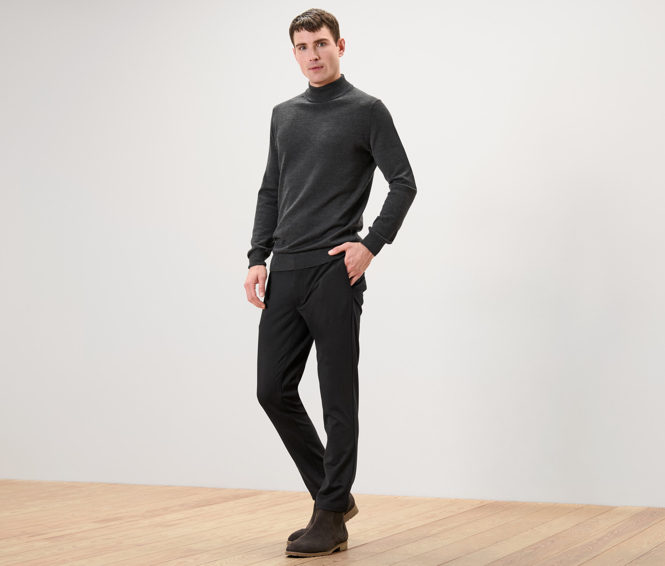 Mężczyzna pozuje do kamery w czarnych spodniach ze stretchu.