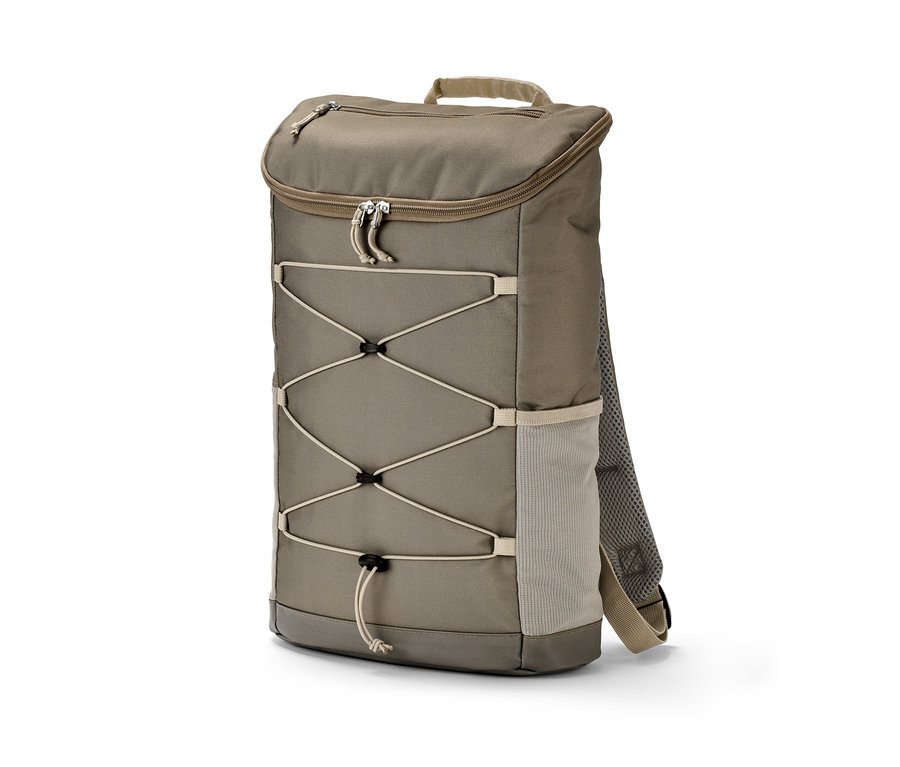 Beżowy plecak outdoorowy stoi na ziemi.