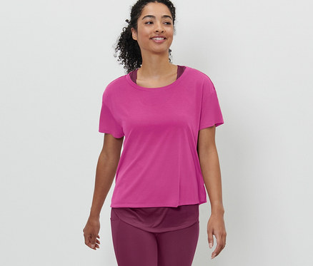 Kobieta idzie i ma na sobie różową koszulkę sportową z krótkim rękawem 2 w 1.
