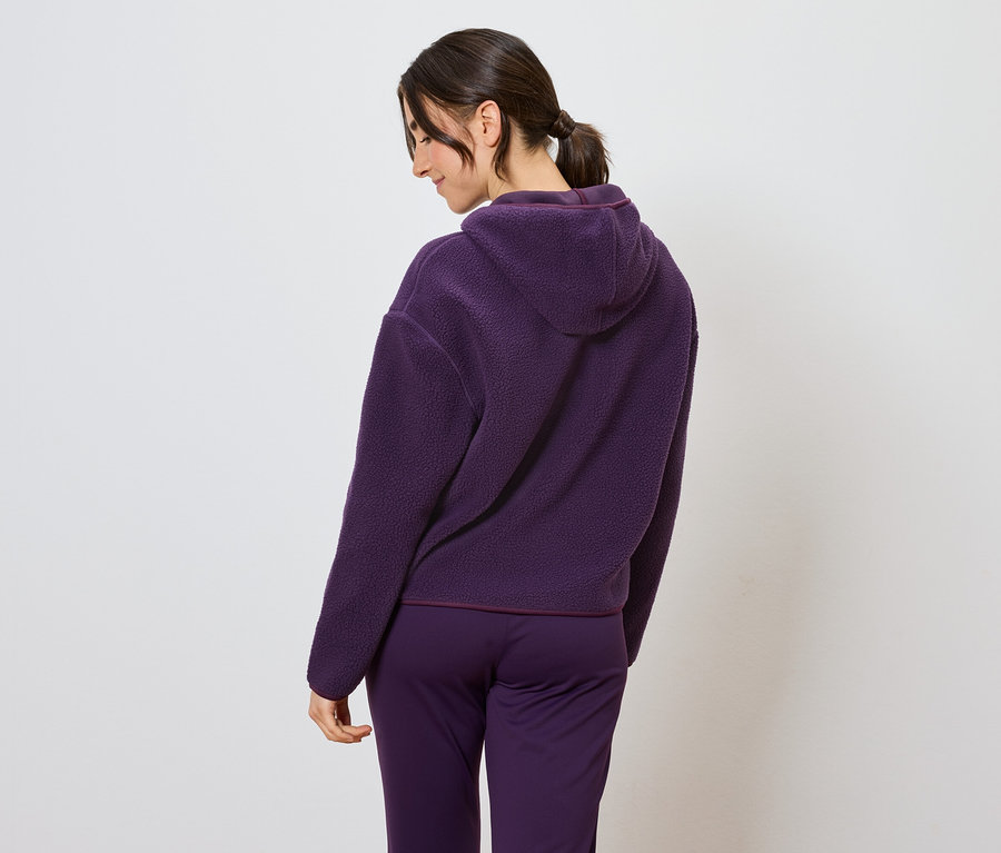 Kobieta w fioletowym dresie z kapturem, widziana z tyłu.