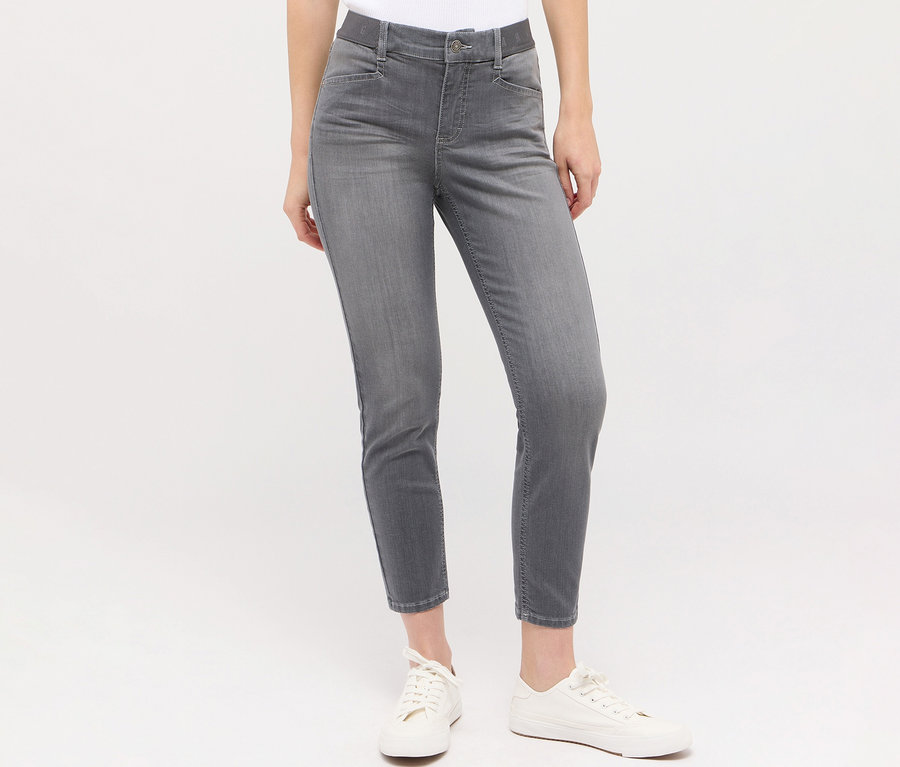Kobieta ma na sobie dżinsy Angels „Ornella Sporty” Slim Fit 7/8 i białe tenisówki.