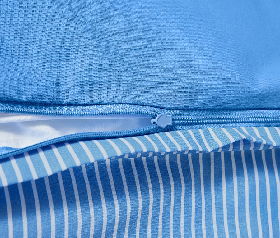 Zbliżenie na pościel z bawełny renforcé z zamkiem błyskawicznym i wzorem w niebiesko-białe paski.