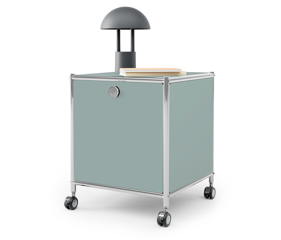 Szara lampa i książka na niebiesko-zielonym pojemniku na kółkach.