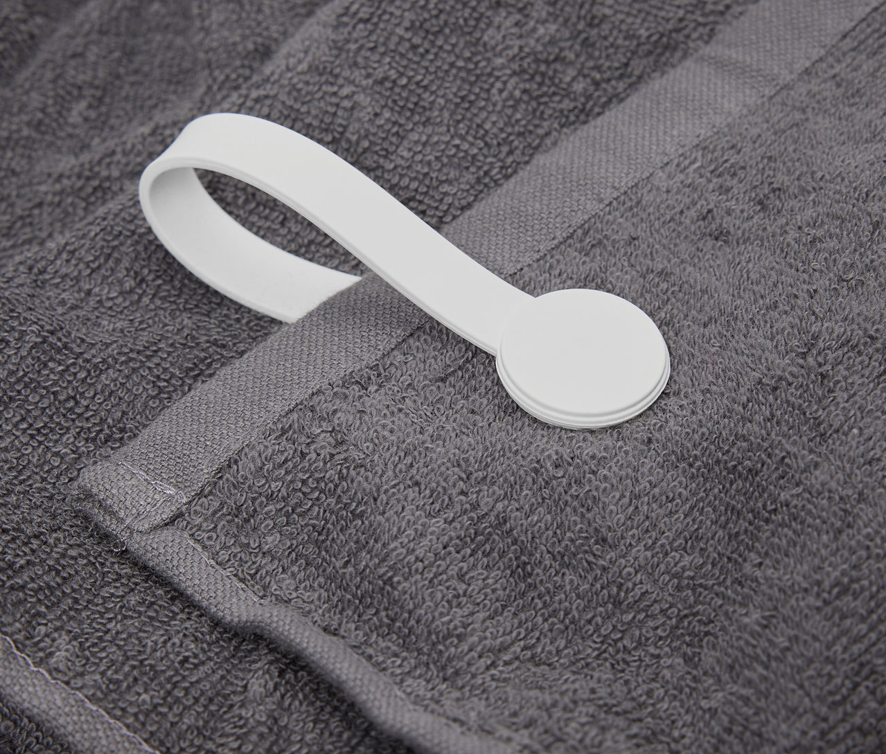 Szczegół szarego ręcznika z białą pętelką.