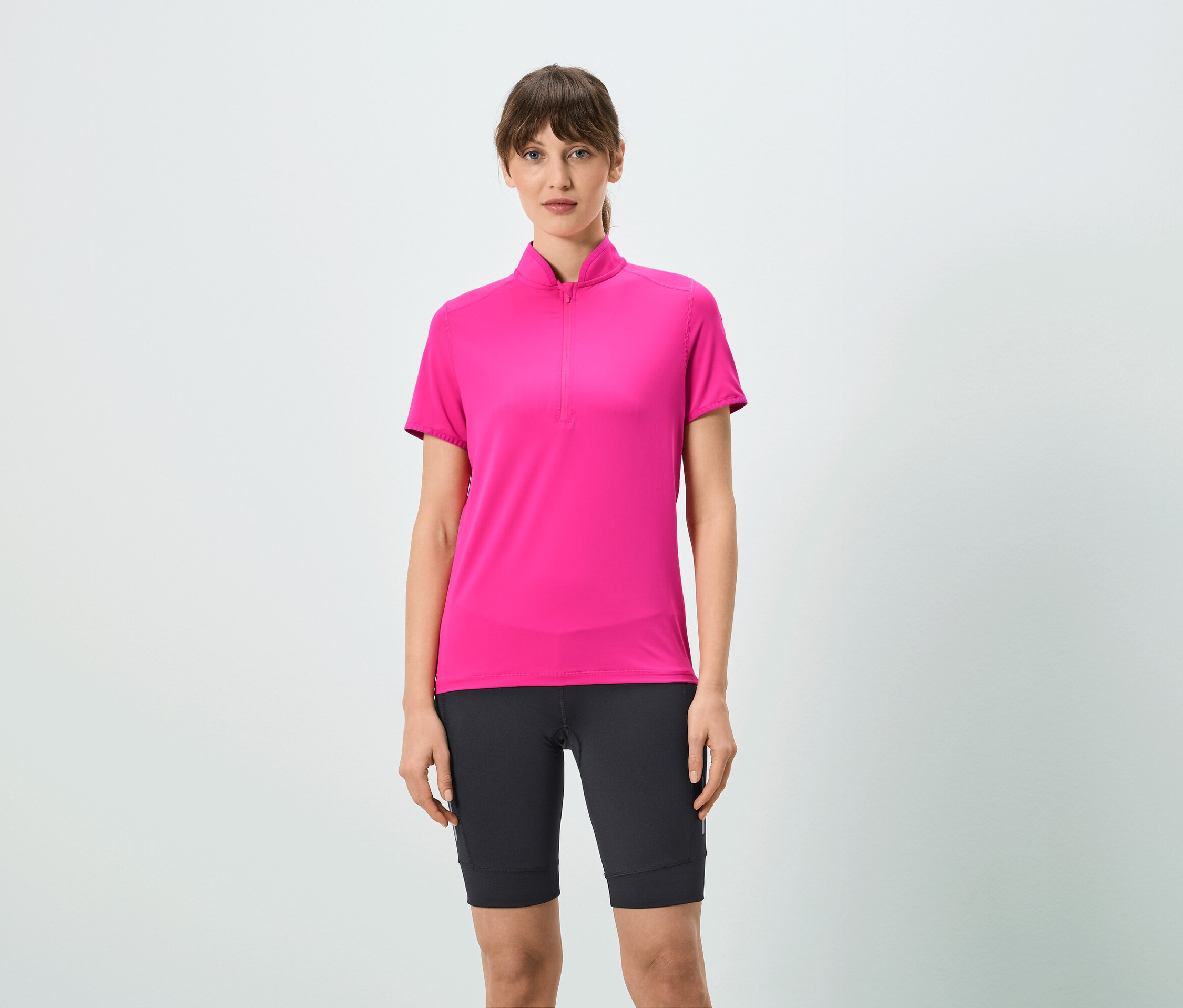 Kobieta ma na sobie różową koszulkę z krótkim zamkiem i czarne szorty.