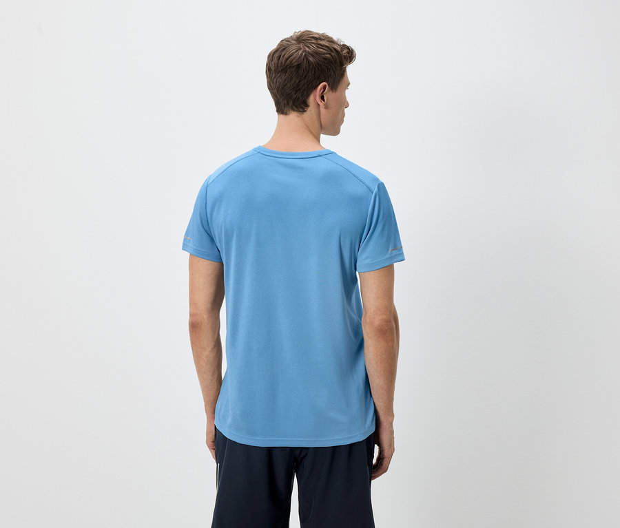 Widok z tyłu mężczyzny o jasnobrązowych włosach, ubranego w niebieską koszulkę i czarne szorty na białym tle.