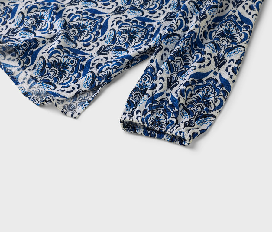 Zbliżenie na biało-niebieski wzorzysty rękaw bluzki.