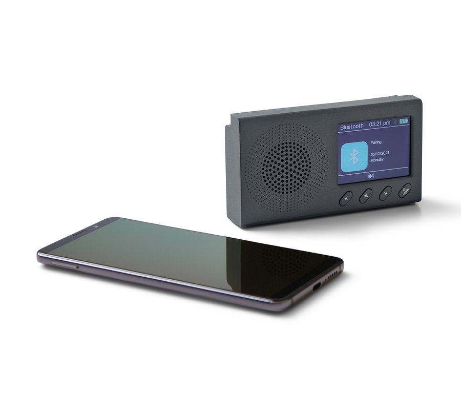 Czarne przenośne radio DAB/FM z Bluetooth i czarny smartfon leżą na białym tle.