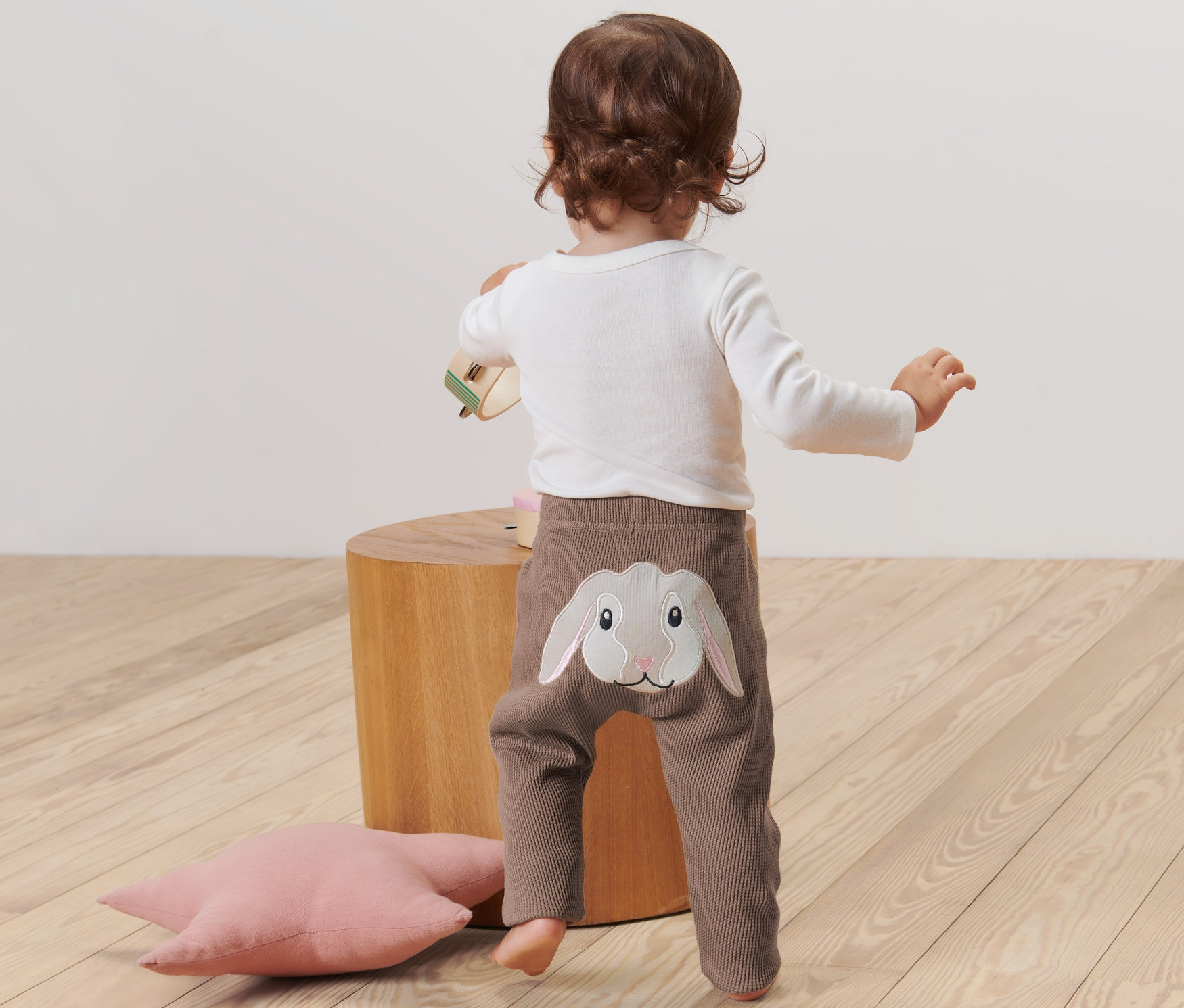 Dziecko stoi tyłem, ubrane w spodnie z aplikacją królika.