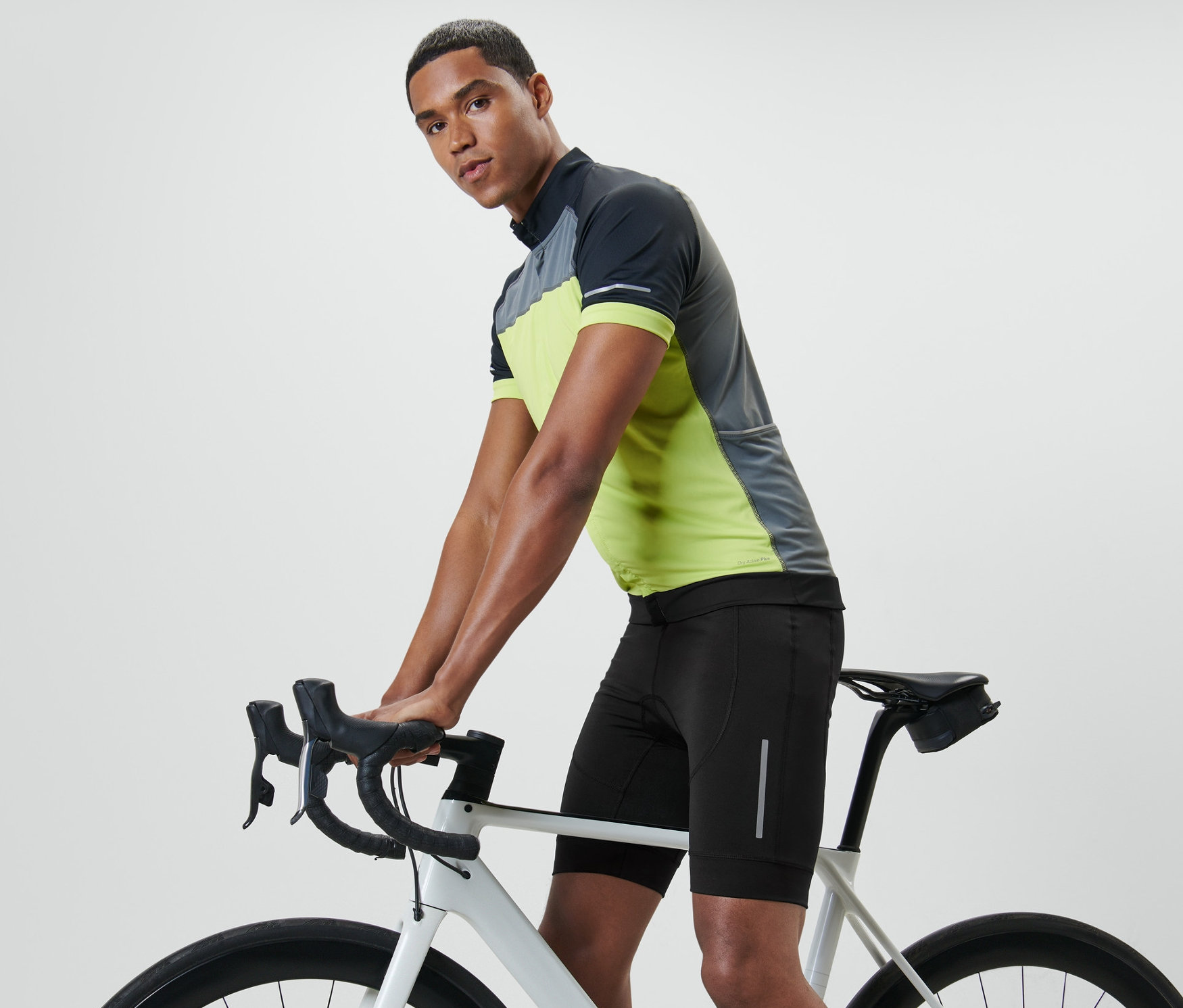 Mężczyzna oparty o kierownicę roweru ma na sobie spodenki rowerowe.