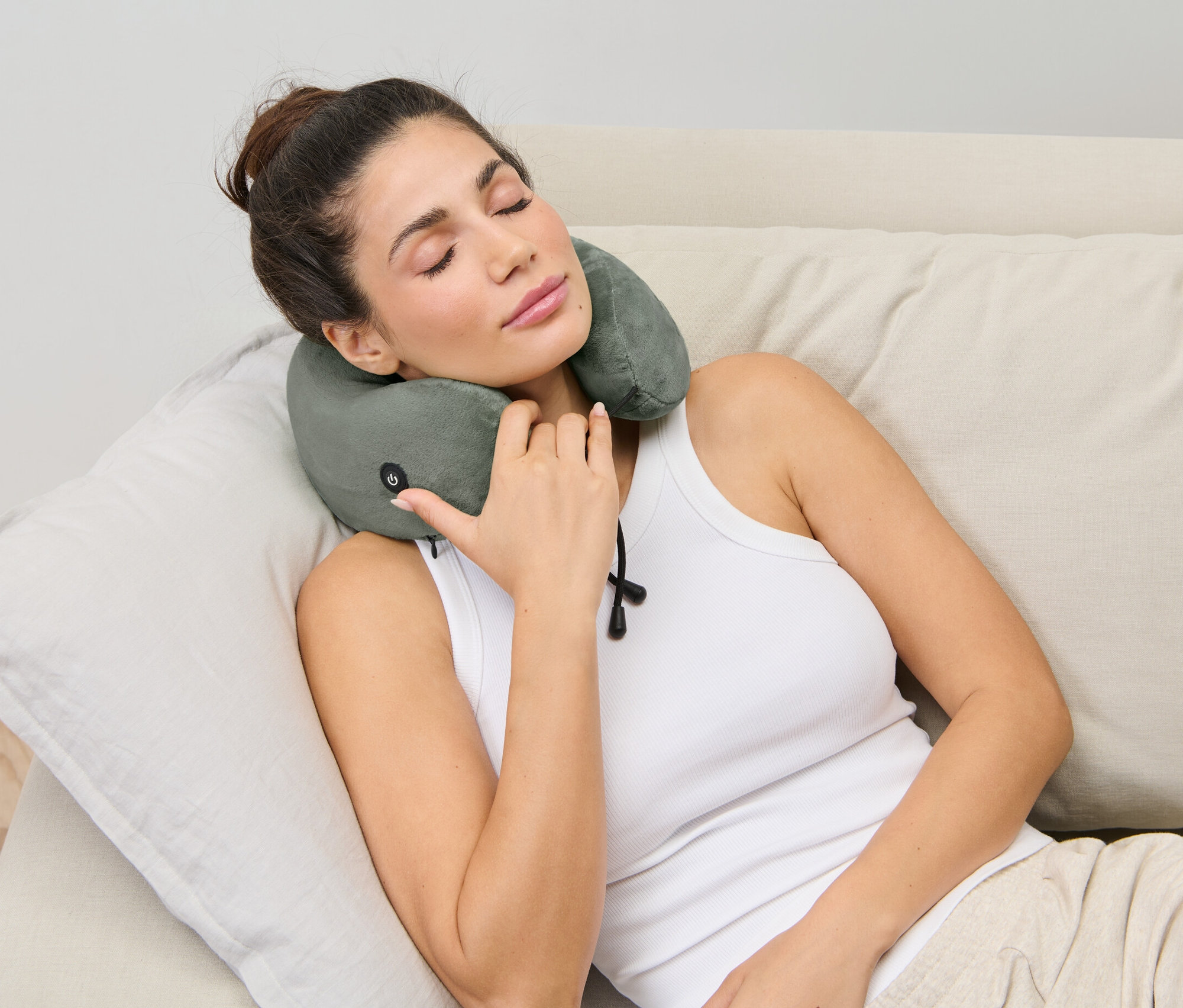 Kobieta leży na kanapie z poduszką na kark z masażem wibracyjnym.