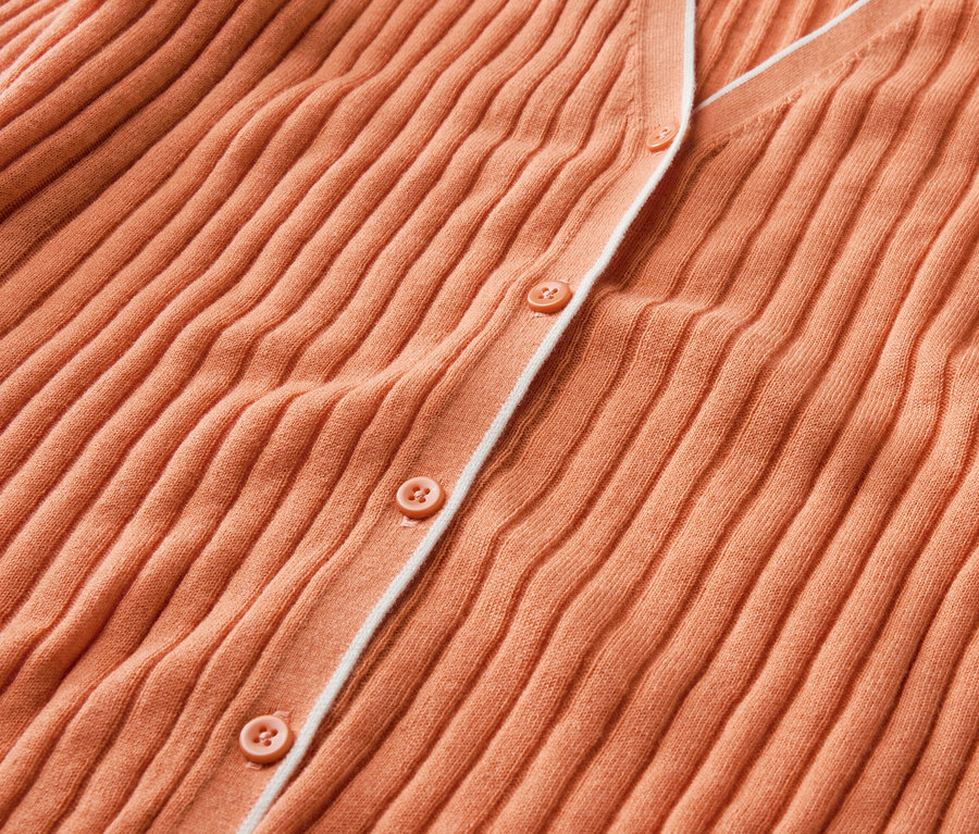 Zbliżenie na pomarańczowy kardigan z guzikami i jedwabiem.