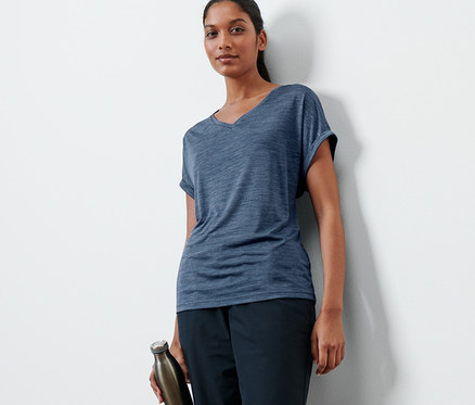 Kobieta pozuje w granatowej koszulce funkcyjnej i trzyma butelkę z wodą.