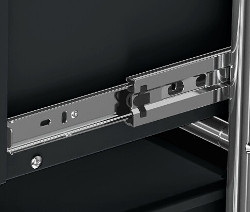 Zbliżenie na wysuwaną szufladę czarnego metalowego mebla.