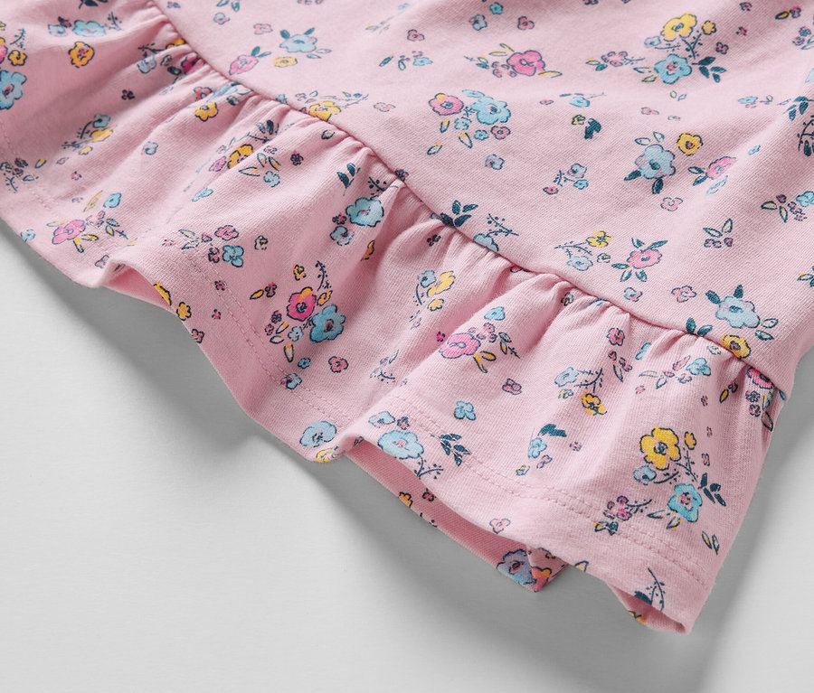 Zbliżenie na różową sukienkę dżersejową w kwiaty z falbaną.