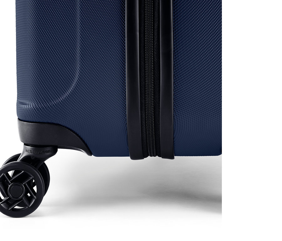 Szczegół niebieskiej walizki z twardą skorupą, z zamkiem błyskawicznym i kółkami.