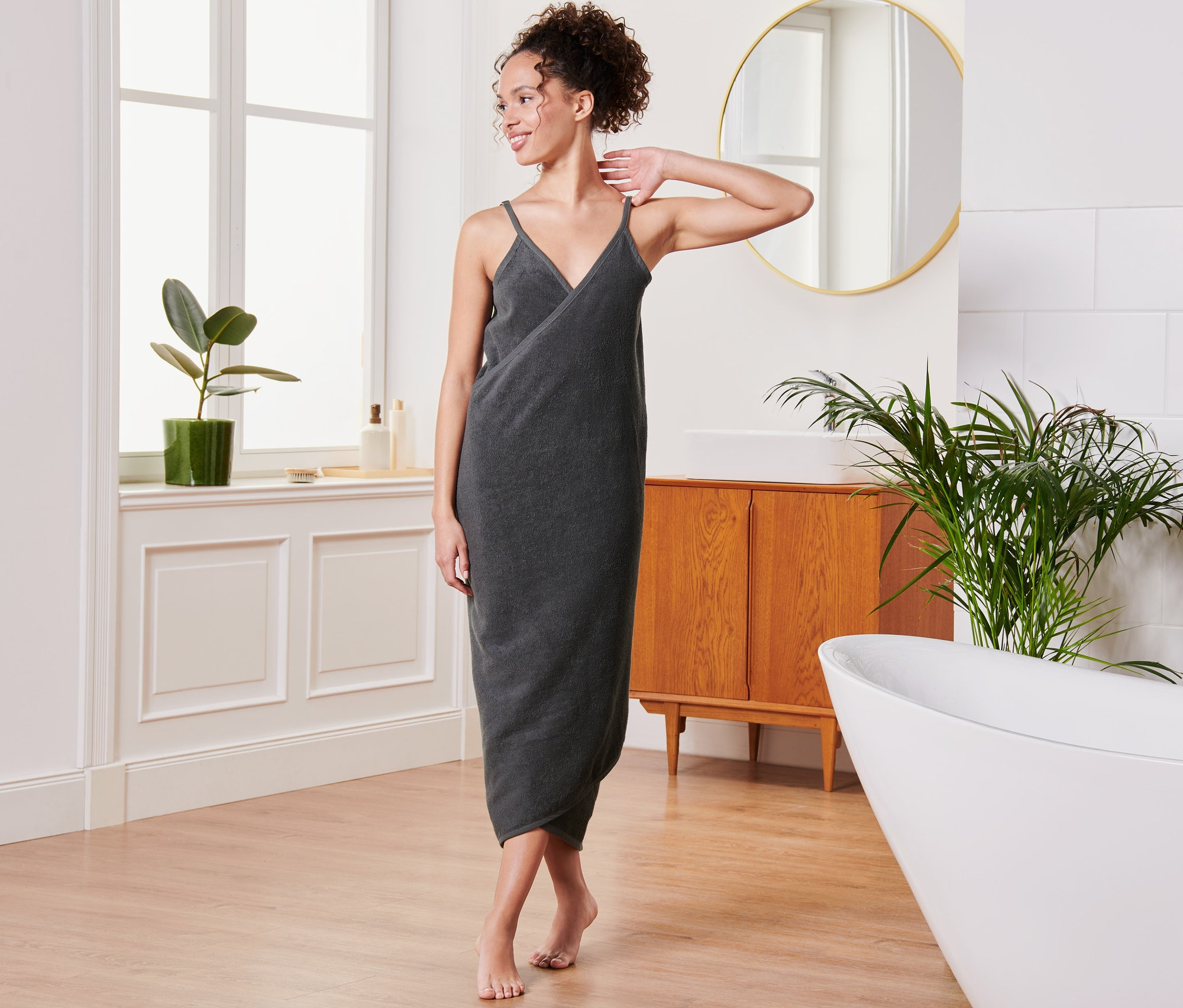 Kobieta pozuje w łazience w antracytowej sukience ręcznikowej.