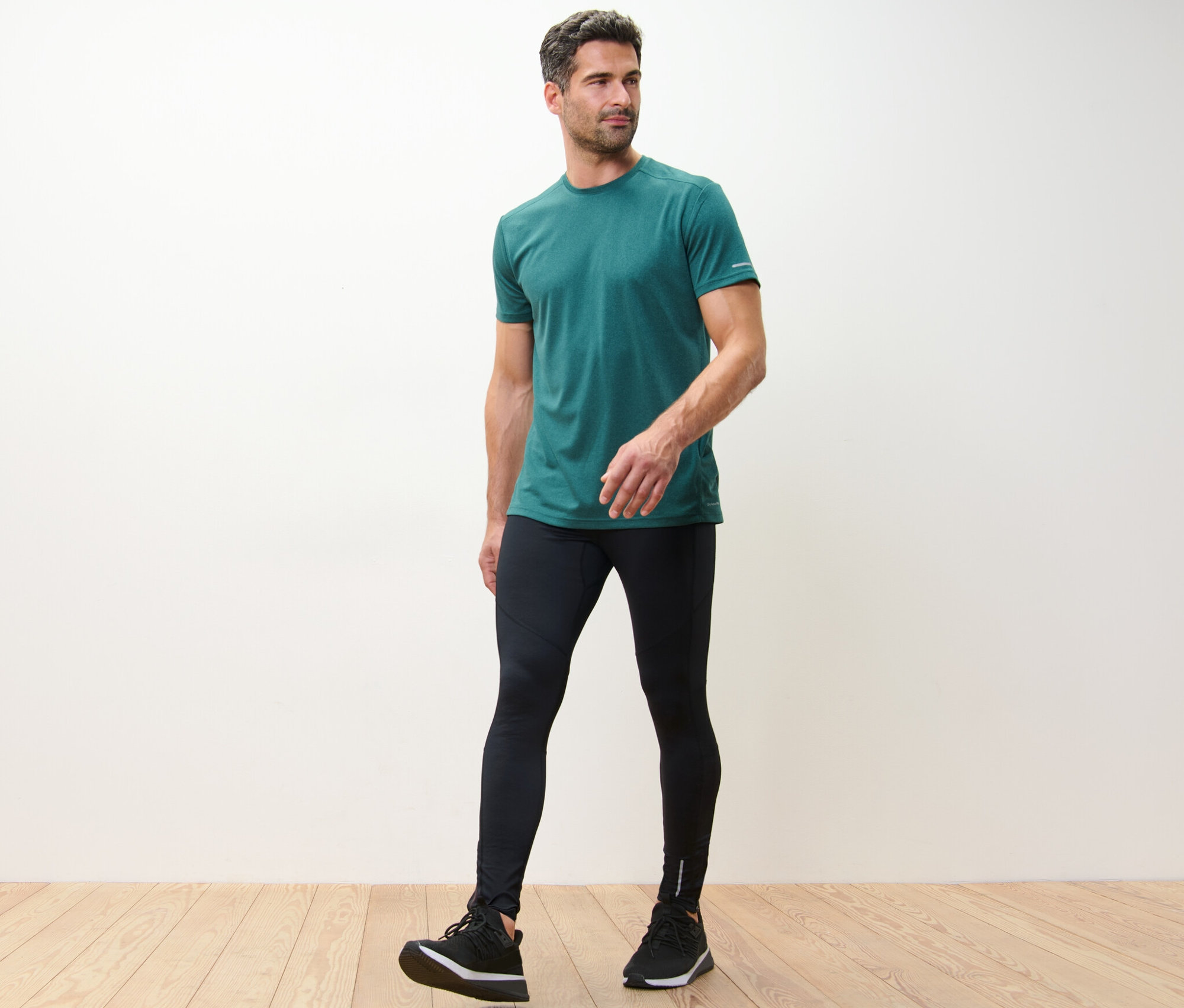 Mężczyzna w zielonej koszulce i czarnych legginsach do biegania.