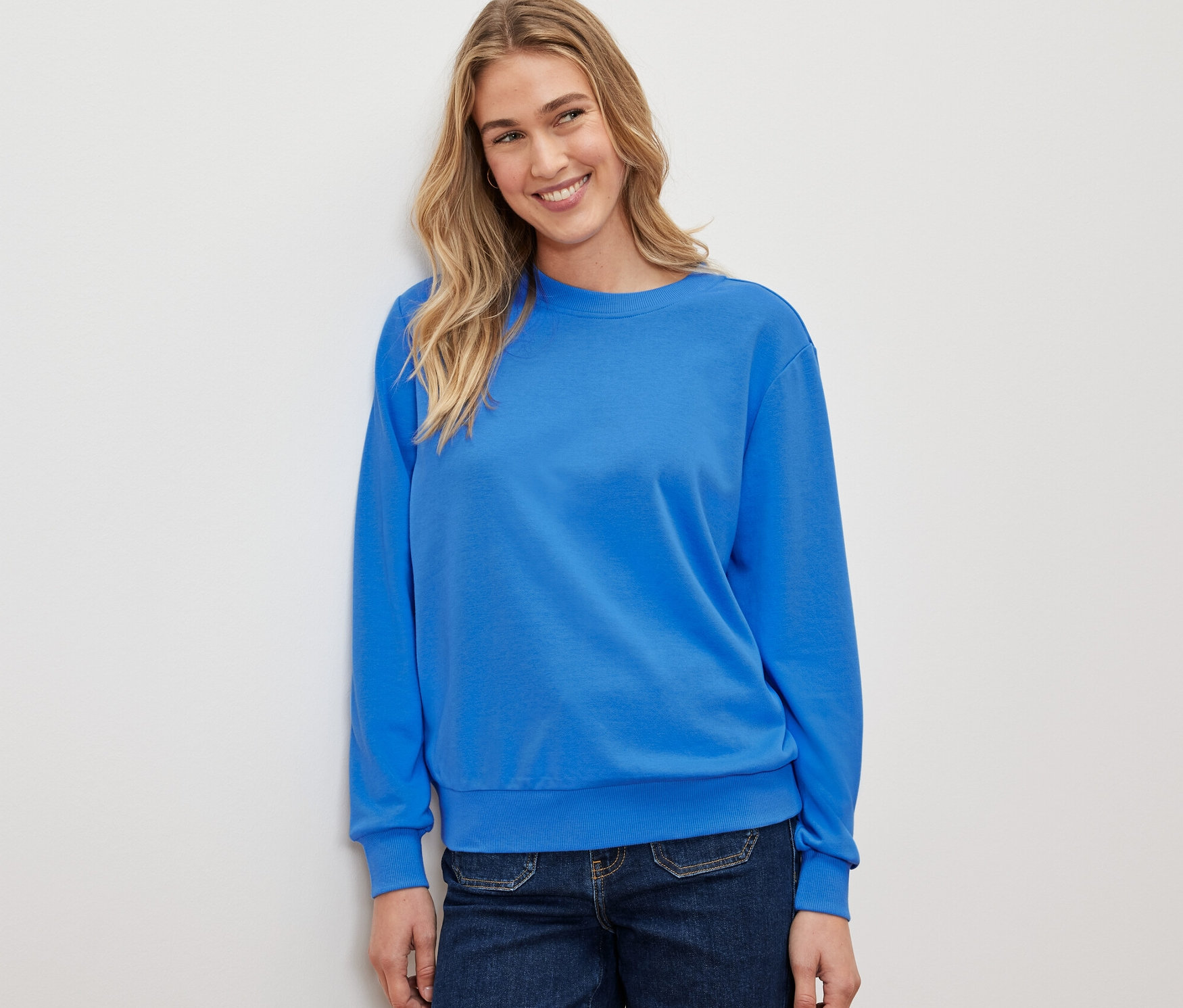 Kobieta ma na sobie kobaltową bluzę.