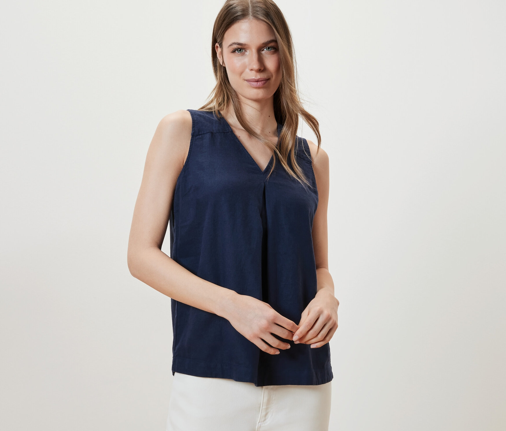 Kobieta pozuje w granatowej lnianej bluzce bez rękawów.