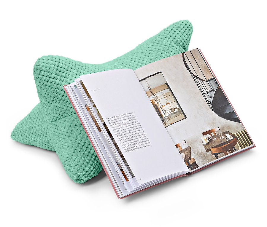 Miętowa poduszka do czytania podpiera otwartą książkę.