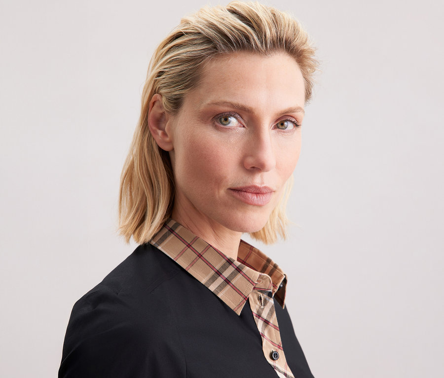 Kobieta ma na sobie popelinową bluzkę Seidensticker z detalami w kratę.