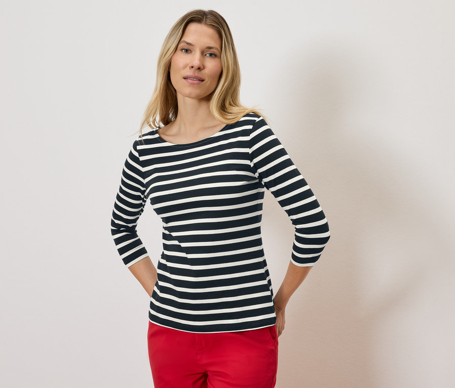 Blondynka w pasiastym trzyczwartym rękawie i czerwonych spodniach.