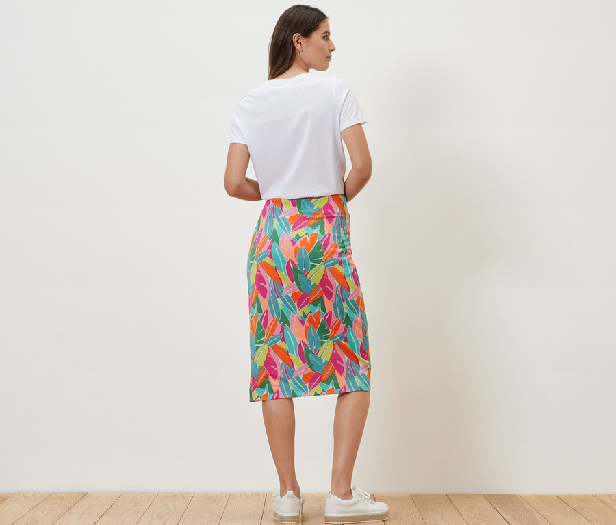 Kobieta stoi tyłem w dżersejowej spódnicy kopertowej.