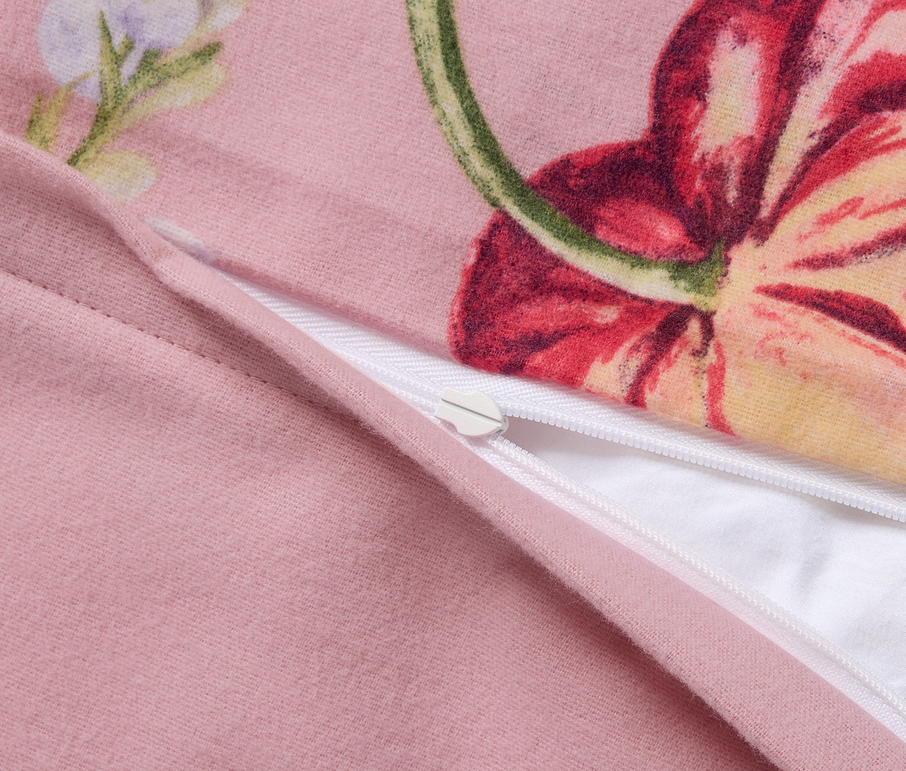 Zbliżenie różowej pościeli z flaneli w niestandardowym rozmiarze we wzory kwiatowe, zapinanej na zamek błyskawiczny.
