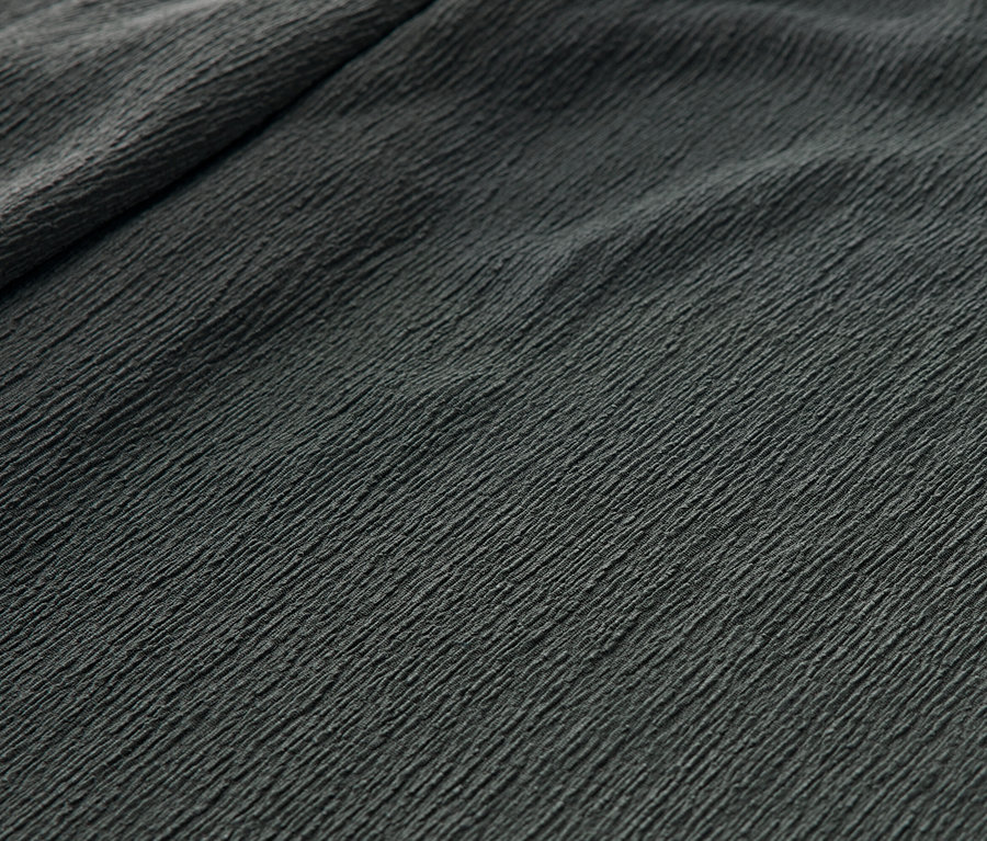 Zbliżenie na zielone spodnie na gumce z efektem marszczenia.