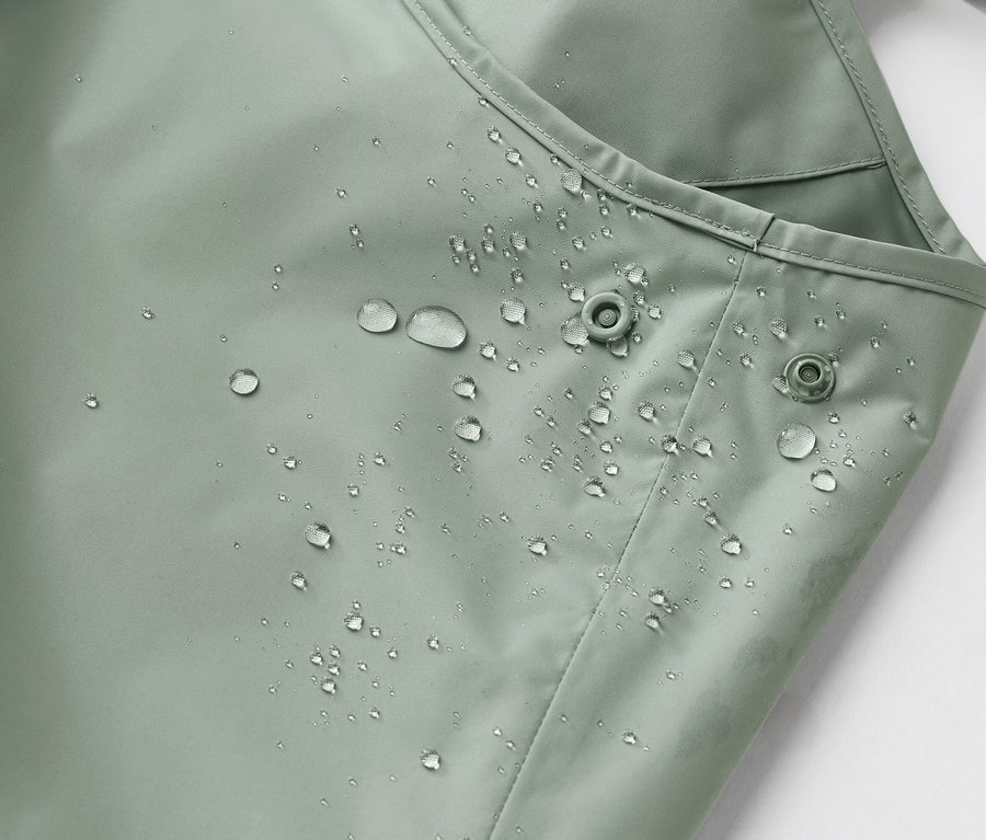 Zbliżenie wodoodpornego, jasnozielonego materiału z kroplami wody i dwoma zatrzaskami.