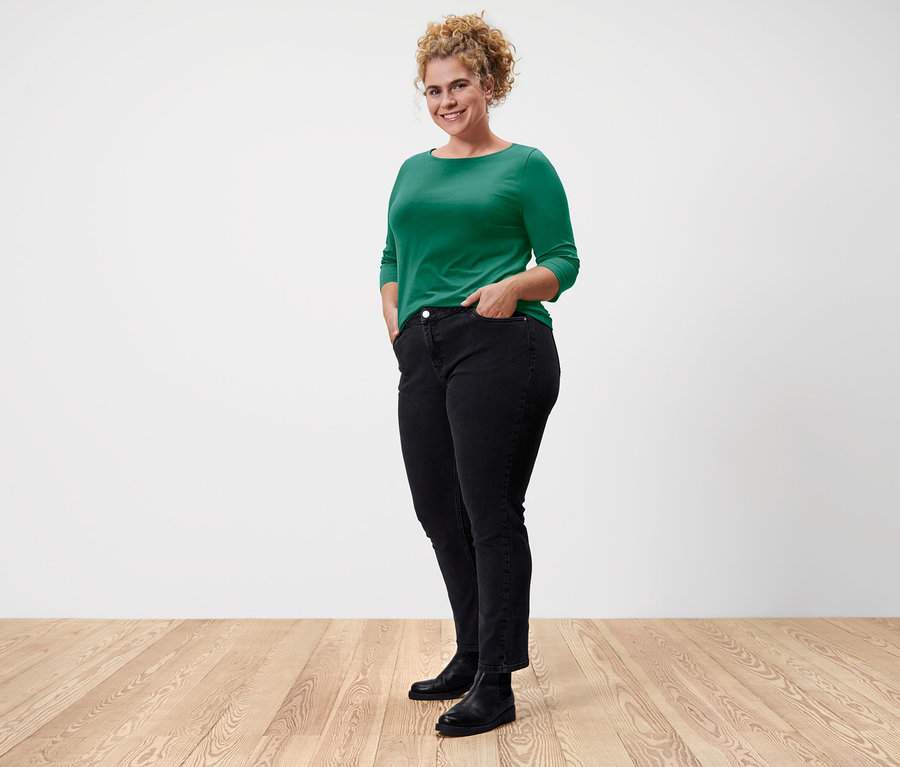 Kobieta pozuje w zielonej koszulce z rękawami 3/4.